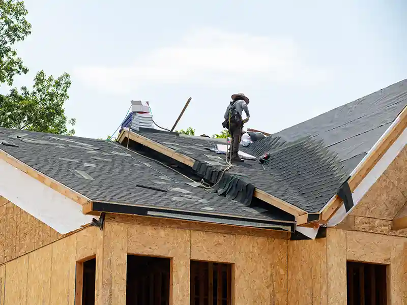 Roofer installing new shingles on a new construction home